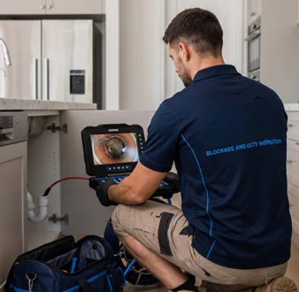 Plumber clearing a blocked toilet in a Fairlight bathroom